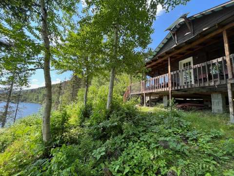 The Pygargue cottage features a covered deck with a view of the lake surrounded by forest.