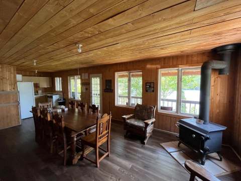 The open area of the chalet includes a dining room, a functional kitchen, and a wood stove.