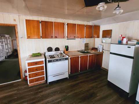 La cuisine équipée du chalet comprend une cuisinière, un réfrigérateur et des espaces de rangement.
