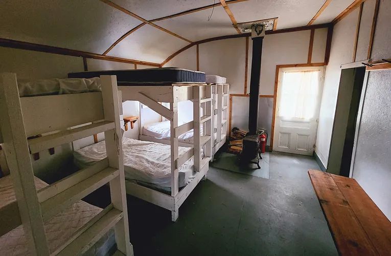 L'intérieur du chalet comprend plusieurs lits superposés et un poêle à bois.