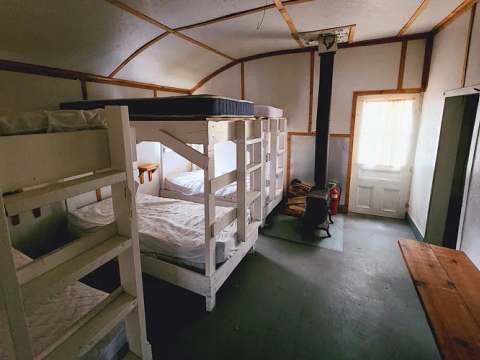 L'intérieur du chalet comprend plusieurs lits superposés et un poêle à bois.