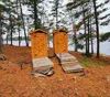Deux toilettes sèches extérieures en bois situées près de la forêt et du lac.