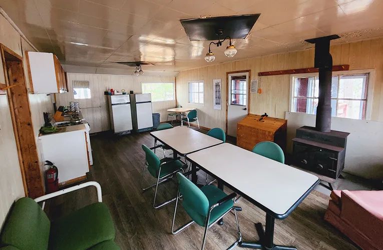 La cuisine et l'espace de repas du chalet incluent une table, des chaises et un poêle à bois.