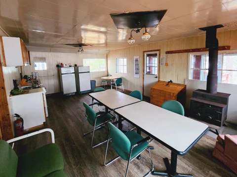 La cuisine et l'espace de repas du chalet incluent une table, des chaises et un poêle à bois.