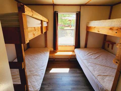 Cette chambre de chalet comprend deux lits superposés en bois avec literie.