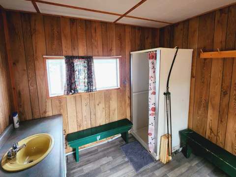 Cette salle de bain fonctionnelle est équipée d'une douche, d'un lavabo et de bancs de rangement.