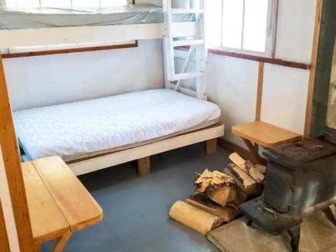 Cette chambre de chalet comprend des lits superposés et un poêle à bois pour votre confort.