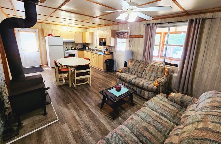 L'aire ouverte du chalet comprend une cuisine équipée, une table à manger et un salon avec poêle à bois.