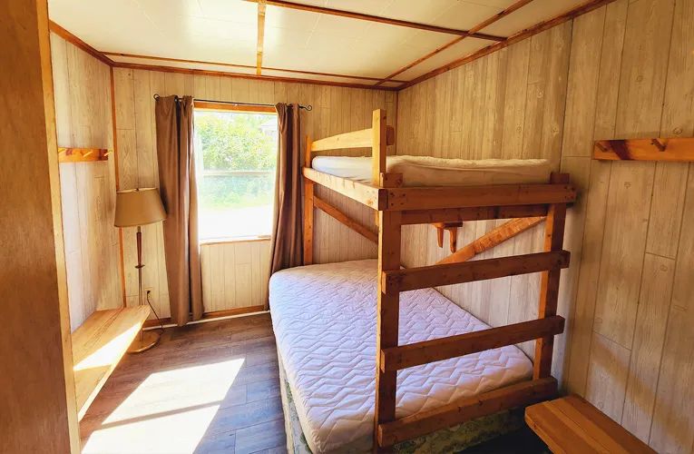 Cette chambre du cottage est équipée d'un lit superposé en bois et d'une lampe de chevet.