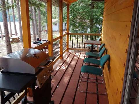 La galerie couverte du chalet dispose d'un barbecue et d'un espace pour se détendre face au lac.