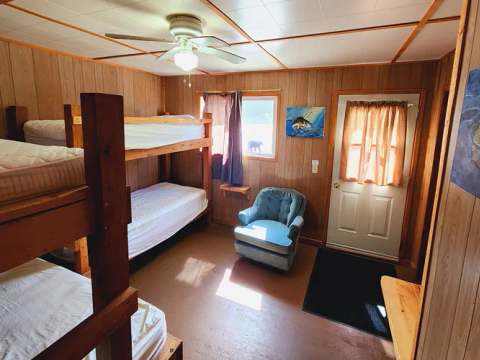 The bedroom of Suite F is equipped with wooden bunk beds and a comfortable armchair.