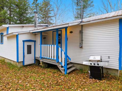 Vue de l'extérieur du chalet numéro quinze avec son entrée et son barbecue.