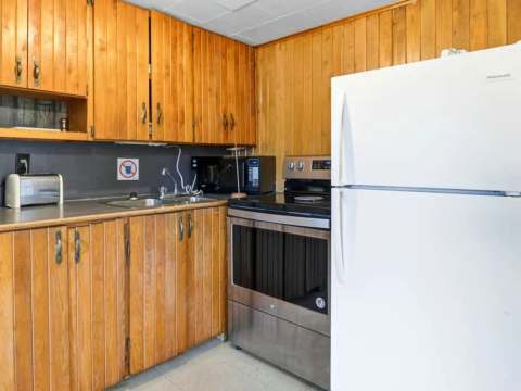 La cuisine équipée du chalet comprend un réfrigérateur, une cuisinière et des espaces de rangement.