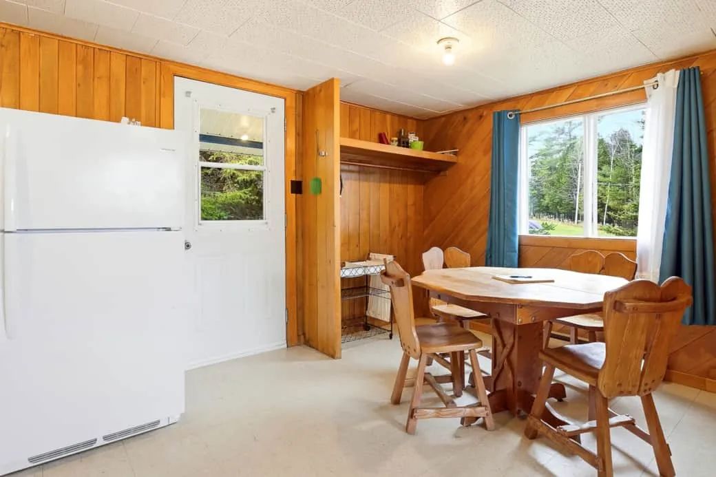 La salle à manger du chalet comprend une table en bois et un réfrigérateur.