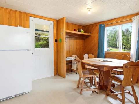 La salle à manger du chalet comprend une table en bois et un réfrigérateur.