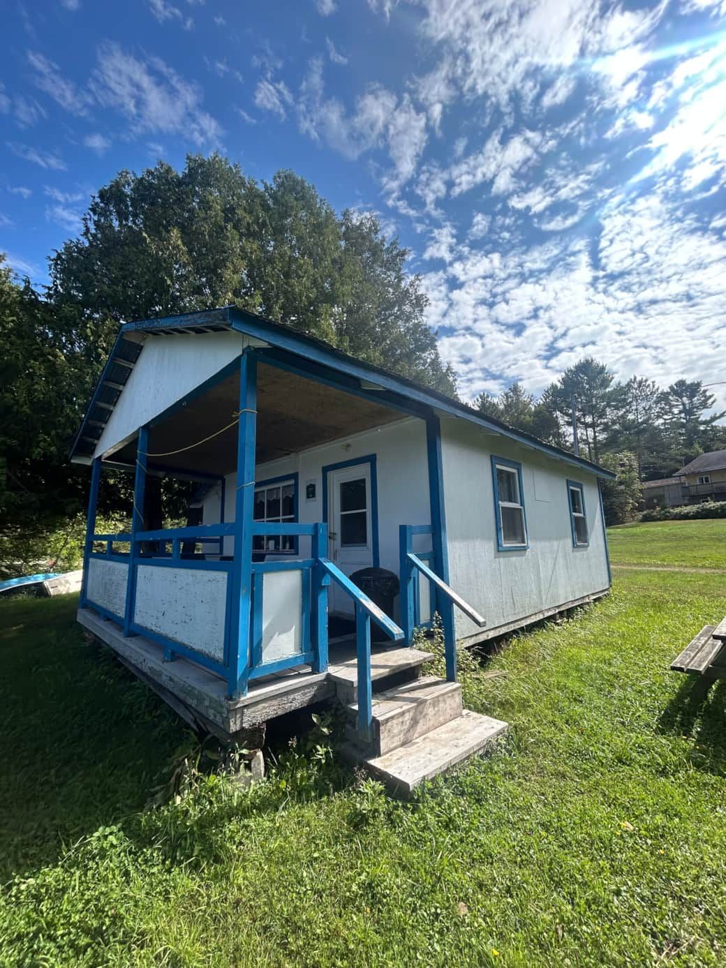 Exterior view of cottage number 11 with its covered porch and grassy grounds.