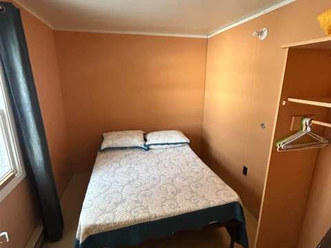 Cette chambre du chalet comprend un lit double avec rangement ouvert.