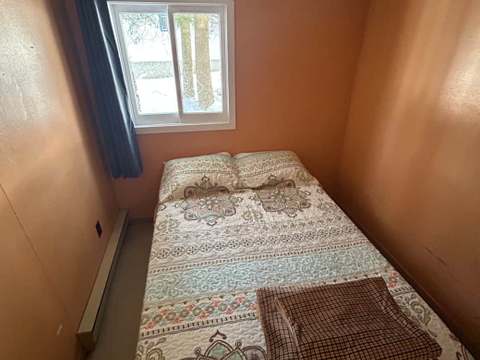 Une des chambres du chalet 16 avec un lit simple et une literie à motifs.