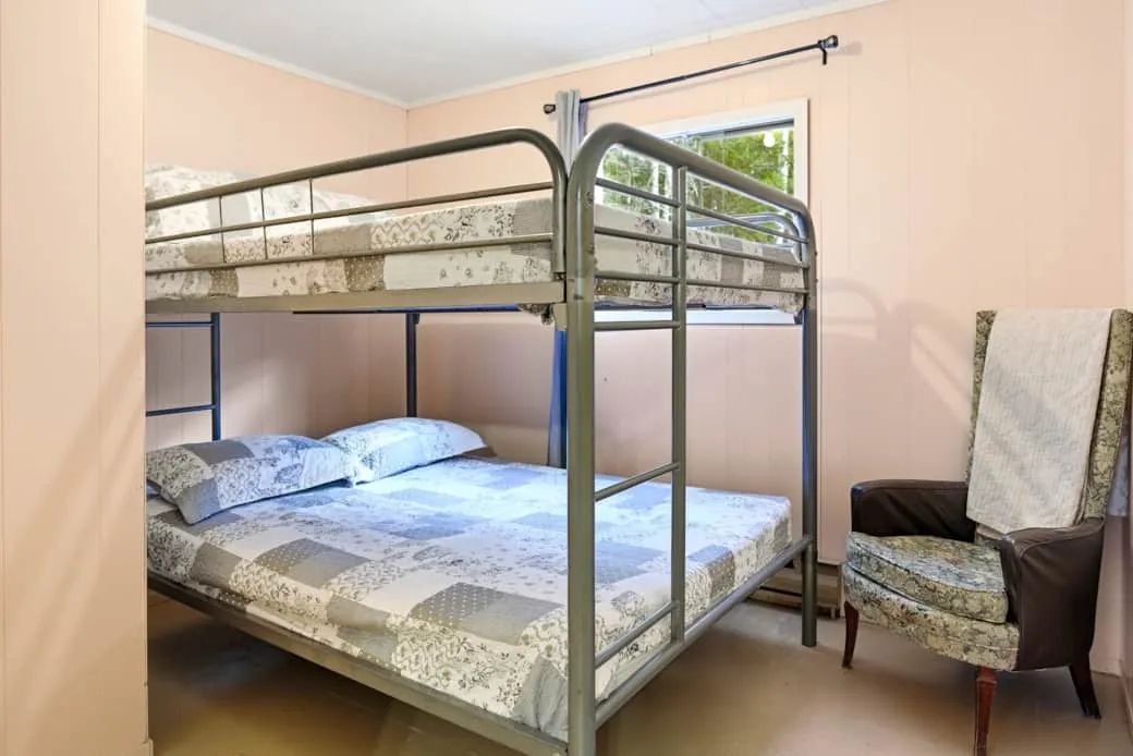 This cottage bedroom features a bunk bed with a double mattress on the bottom.