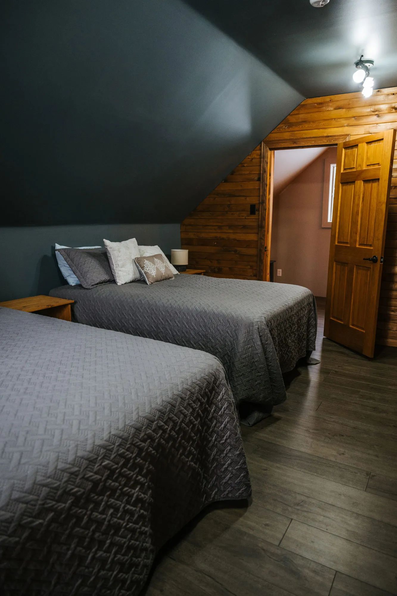 Cette chambre comporte deux lits confortables sous un plafond mansardé en bois.