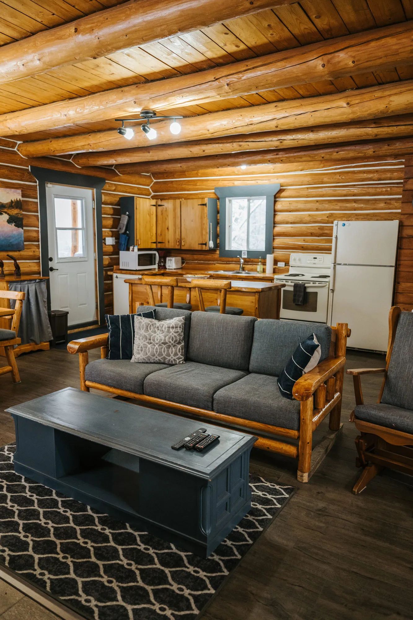 Espace de vie ouvert comprenant un salon confortable et une cuisine équipée dans le chalet en bois rond.