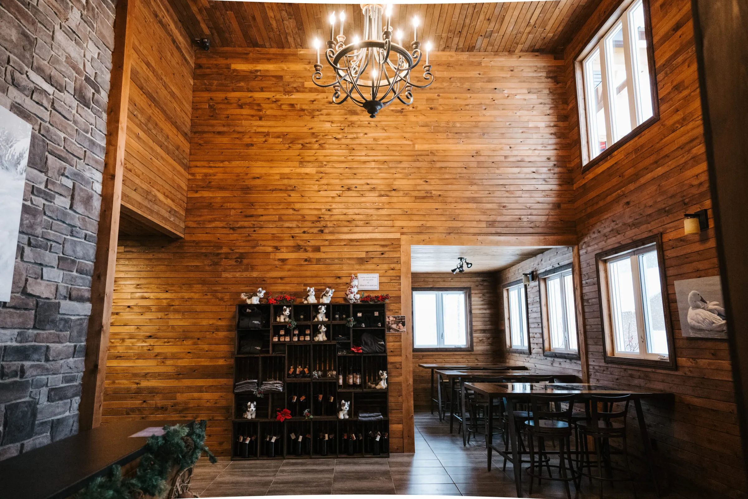 Vue de l'aire commune du lodge avec murs en lambris de bois, foyer en pierre et coin repas.