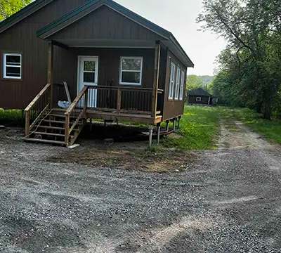 Exterior view of the cottage with its covered gallery and wooden staircase access.