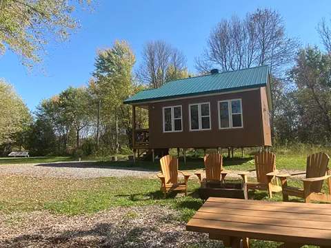 The Lièvre et de la tortue cabin is surrounded by trees with an outdoor fire pit area.