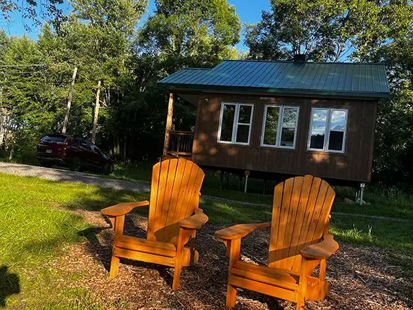 Two Adirondack chairs are set up in front of the Lièvre et de la tortue cottage.
