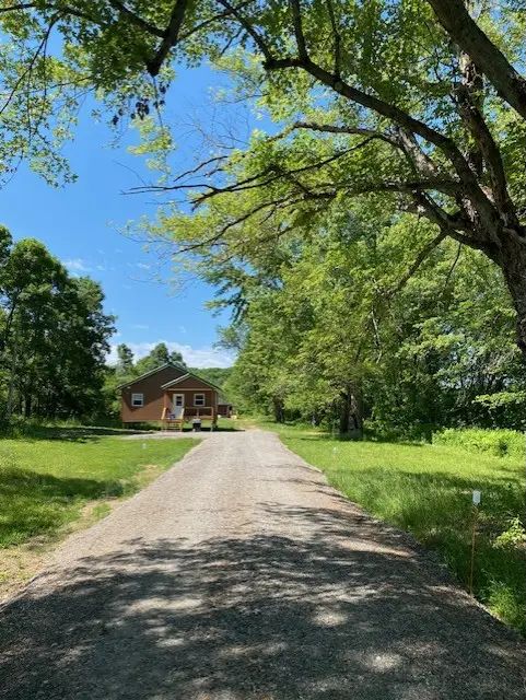 A gravel path leads to the exterior of the cabin surrounded by nature.