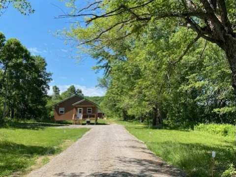 A gravel path leads to the exterior of the cabin surrounded by nature.