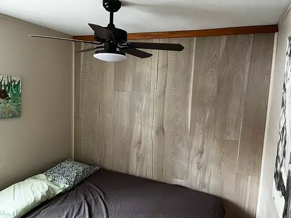 Vue d'une chambre à coucher avec lit et ventilateur au plafond au chalet L'Oasis.