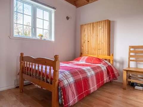 This bright cottage bedroom features a single bed and a wooden chair.