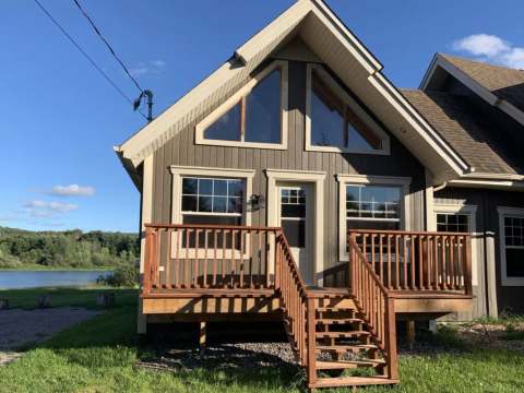 Exterior facade of Les Lucioles cottage featuring its wooden deck and access to the water.