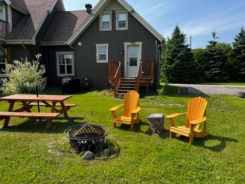 The Les Lucioles cottage offers an outdoor space with a fire pit, picnic table, and Adirondack chairs.