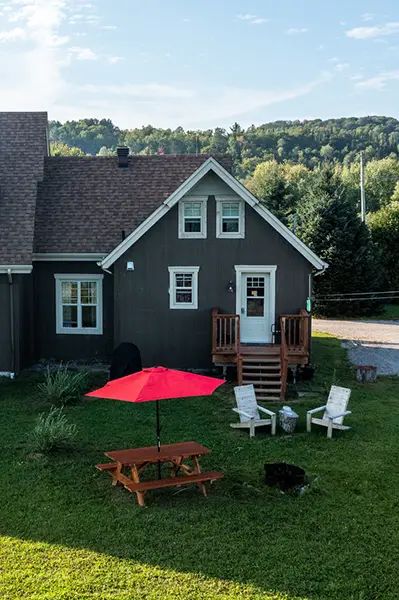 Exterior view of Les Lucioles cottage with its picnic table and Adirondack chairs.