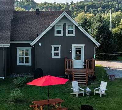 Exterior view of Les Lucioles cottage with its picnic table and Adirondack chairs.