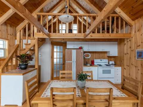 The open-concept cabin features a fully equipped kitchen, a dining area, and a mezzanine.