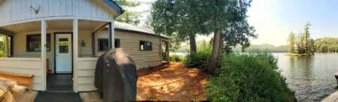Panoramic view of Le Grand Pin cabin with its porch, barbecue, and private dock by the water.