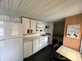 The functional kitchen of the Le Guide cabin includes a refrigerator, a sink, and a table.