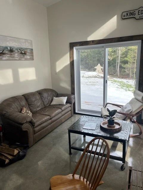The bright living room of the Le Martin pêcheur cabin features a comfortable sofa and an outdoor view.