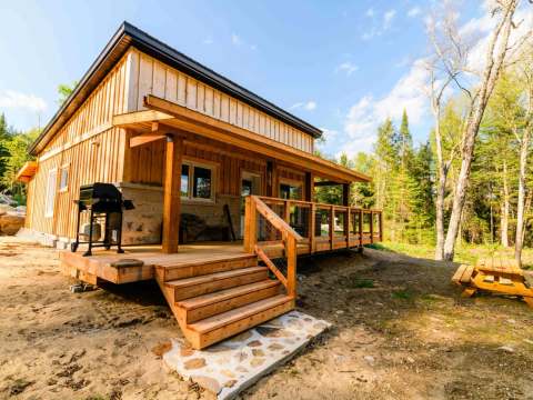Exterior view of the Martin Pêcheur cabin with its covered deck and barbecue.