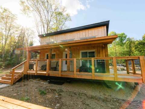 The Le Ruisseau cabin features a large wooden deck surrounded by the forest.