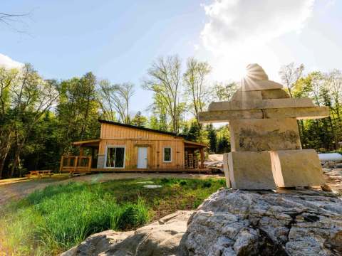 The Martin pêcheur cabin with its outdoor deck and an inukshuk in the foreground.