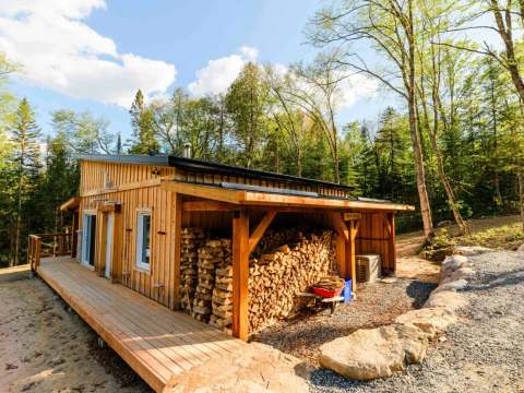 Side view of Le Martin pêcheur cabin with its deck and outdoor wood storage.