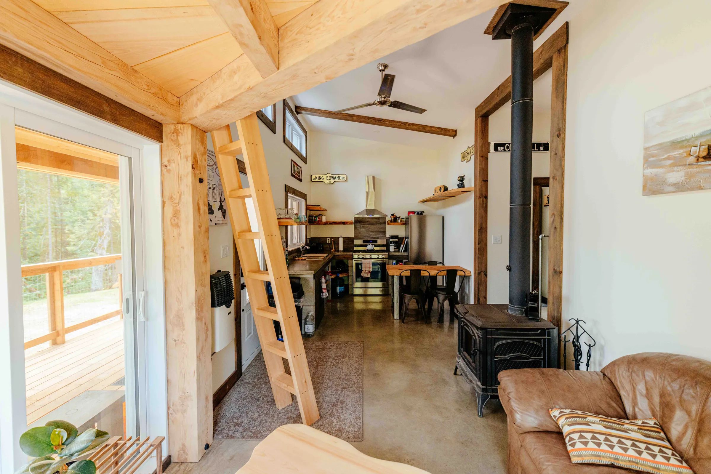 Overview of the open concept living area including the kitchen, wood stove, and deck access.