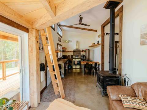 Overview of the open concept living area including the kitchen, wood stove, and deck access.