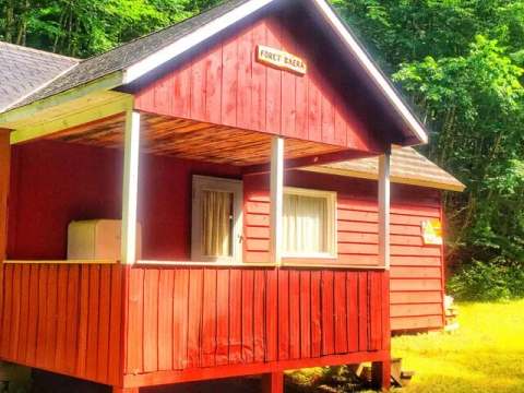 Side view of Le Panache cabin with its covered porch in the forest.