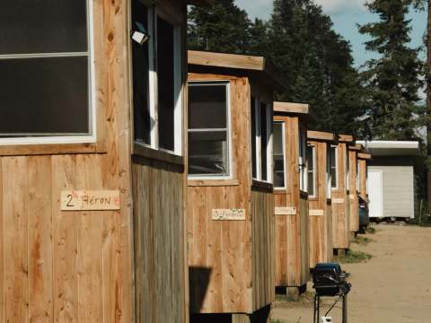Vue latérale des chalets en bois numérotés et identifiés par des noms d'oiseaux.