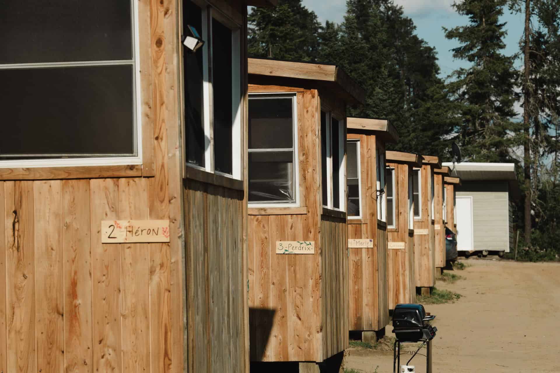 A row of rustic wooden cabins lined up along a dirt path.